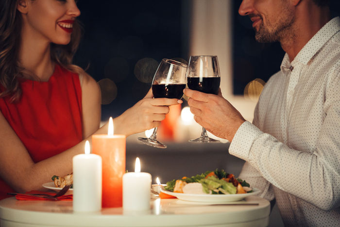 Cropped photo of young lovers having romantic dinner and drinking red wine at home