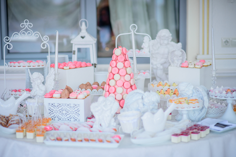 Beautiful candy bar of pink and white sweets decorated with figures of white porcelain angels