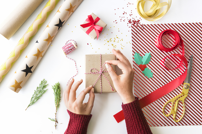 Hand tying bow gift box on white table